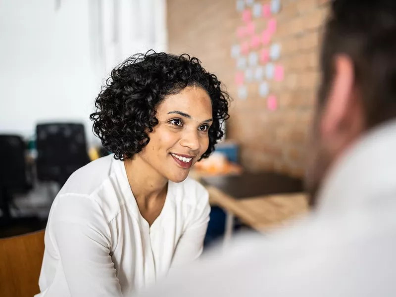 Mid adult woman talking with a colleague at work